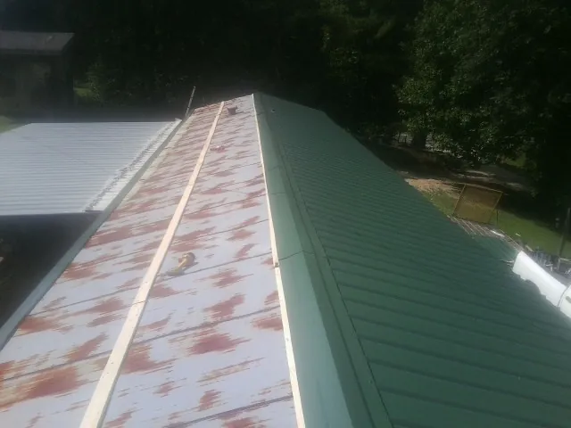 Old rusted panels beside newly installed green metal roofing — Wind Damage Roof Repair by Roofing Brothers in Cooleemee