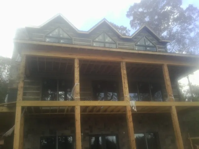 Dormers and porch framing on a large log home under construction — Roof Coating work by our crew in Cooleemee