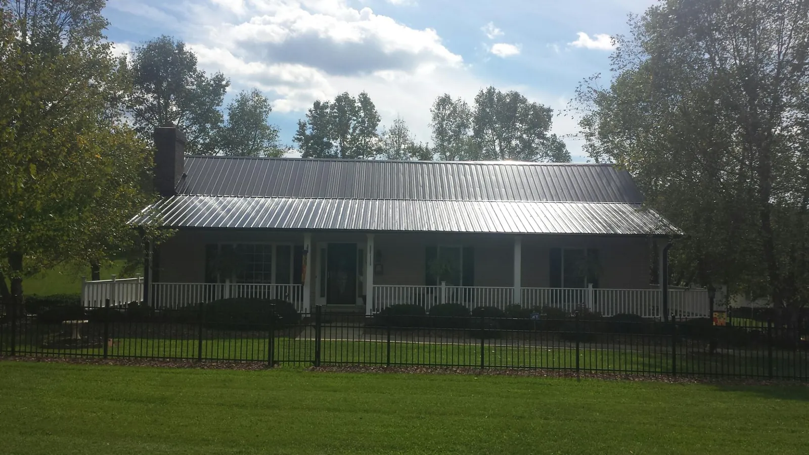 Gray metal roof on a brick ranch with a full width front porch — Gutter Guard Installation work by our crew in Cooleemee