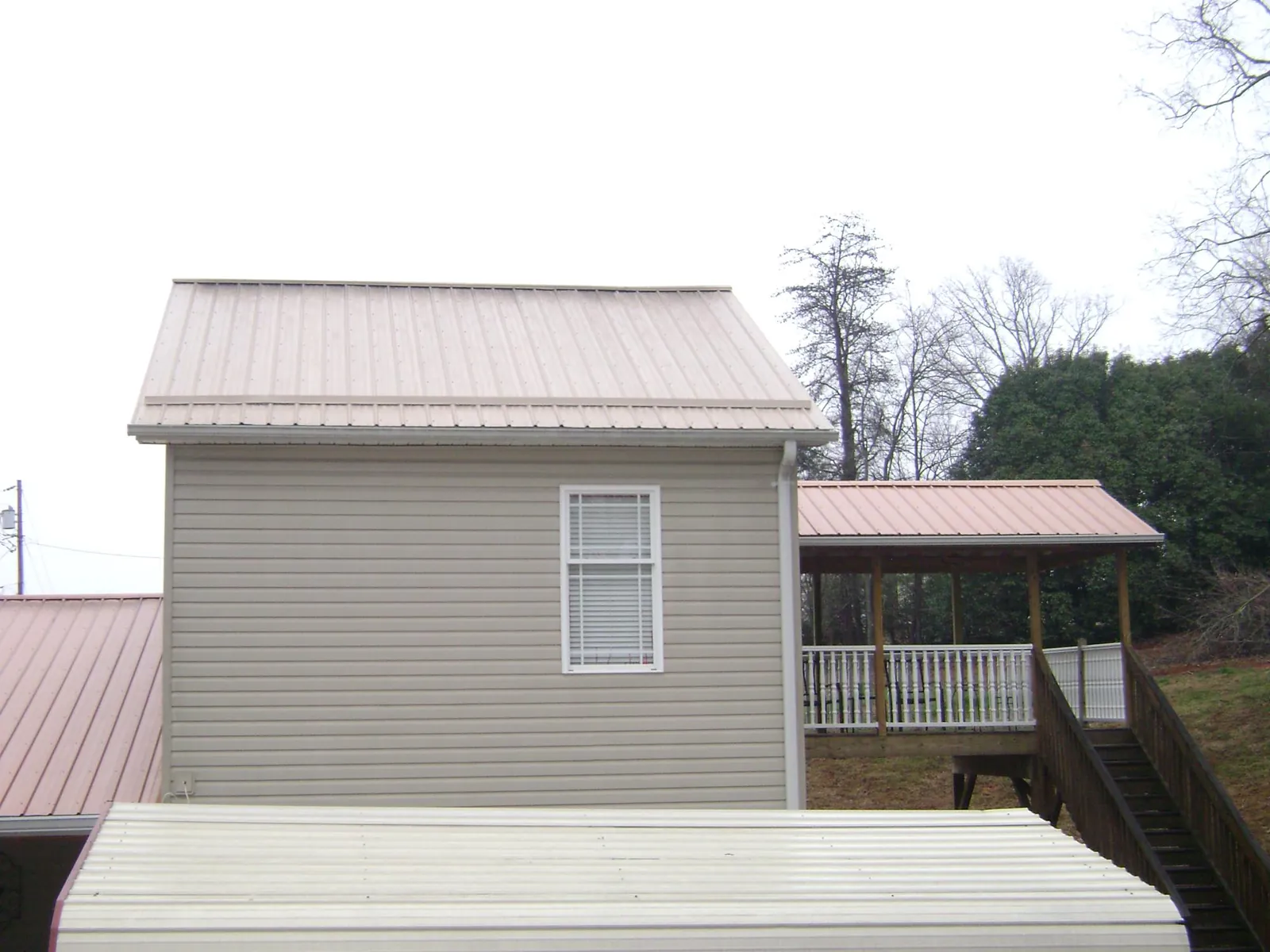 Tan metal roofs on a two story addition and attached porch, from a Roof Replacement job in Cooleemee