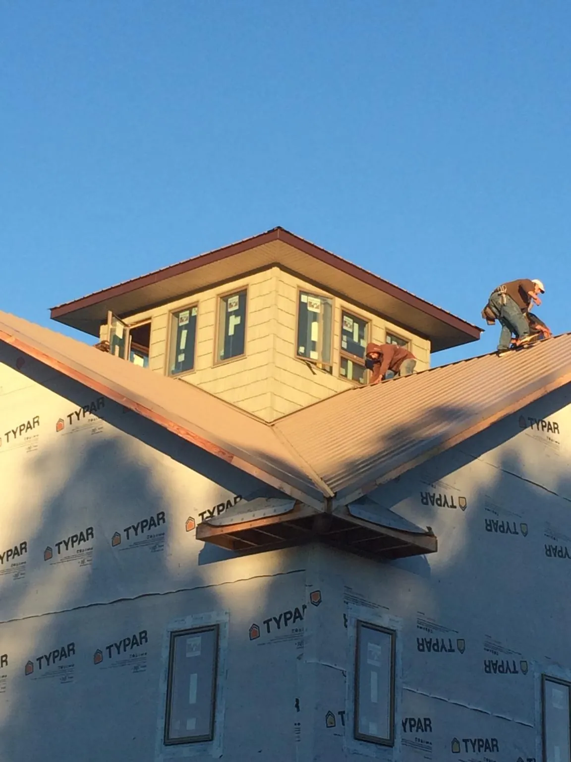 Roofers working around a rooftop cupola on a new metal roof at sunset — Roof Waterproofing in Cooleemee by Roofing Brothers